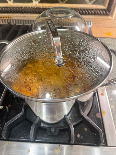 Reviewer cooking the Halal Chicken Ground Meat in a covered stainless steel pot on a stove.