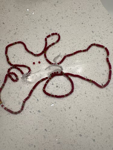 Customer's broken Ruby Luxe Tie On Waist Beads lying on a countertop with the string snapped.