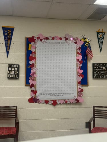 Reviewer's Valentines Day word search puzzle hanging on a bulletin board in a guidance office, decorated with hearts.