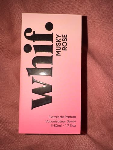 Reviewer's pink gradient product box for Musky Rose perfume, resting on a pink fabric.