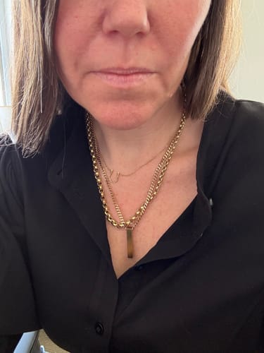 Reviewer wearing the Matte Rectangle Bar Urn Pendant layered with other gold necklaces against a black shirt.