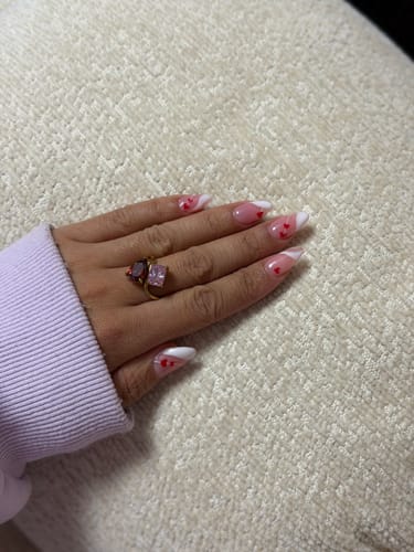 Reviewer's hand wearing the Navae Birthstone Ring, which features a dark reddish and a light pink stone.