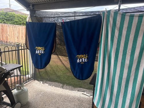 Reviewer's two blue Waterproof Car Towel Seat Covers hanging to dry outside on a clothesline.
