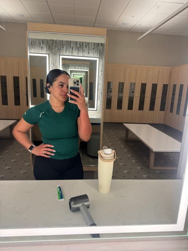 Reviewer in a gym locker room, wearing their jewelry to show its suitability for active wear.