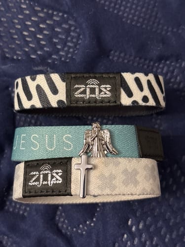 Reviewer's silver Cross Bracelet Charm on a white Zox bracelet, stacked with two other bracelets.