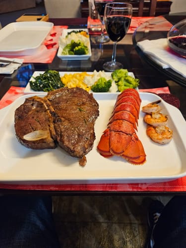 Customer's large Porterhouse Steak cooked and served on a platter with a lobster tail and shrimp.