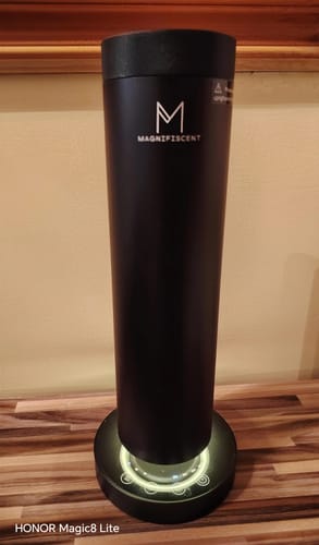 Customer's sleek, black LumaMini diffuser on a wooden surface with its white ambient base light on.