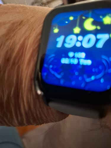 Close-up of a customer wearing the Health smartwatch with a blue digital face displaying the time.