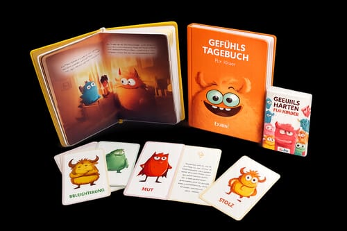 Rezensent zeigt das Gefühlstagebuch für Kinder als Set mit einem aufgeschlagenen Buch und illustrierten Gefühlskarten.