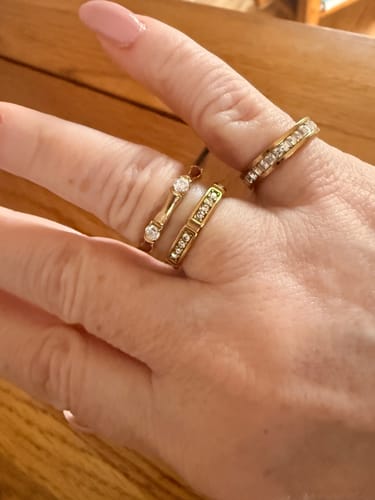 Customer's hand wearing the gold Bamboo Ring With Stones stacked with two other rings.
