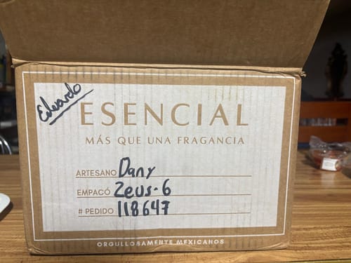 Caja de un cliente que contiene el perfume H275, mostrando la etiqueta de envío de la marca Esencial.