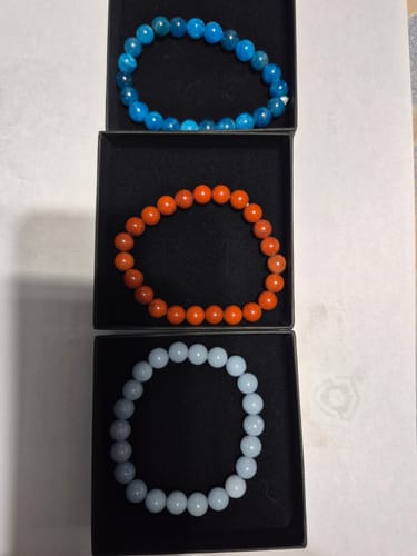 Avis d'un client montrant trois bracelets en perles colorées dans leurs boîtes noires.