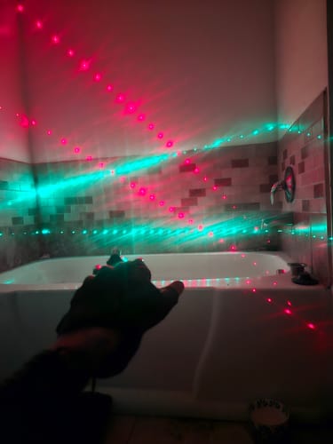 Reviewer's hand wearing the LITLAMP™ Laser Glove, projecting red and green dotted patterns in a dark room.
