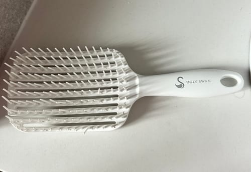 Reviewer's white Scream-Free® Hair Brush on a counter, showing its unique flexible bristles are all intact.