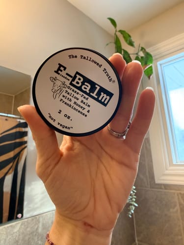 Customer holding the round F-Balm tallow balm tin in their hand.