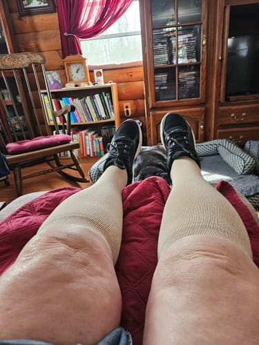 Reviewer relaxing with their feet up, wearing beige Performance Eucalyptus Compression Socks and sneakers.