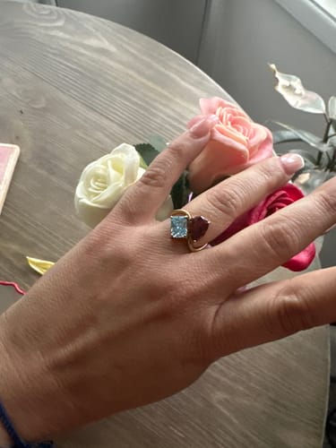 Customer wearing the Navae Birthstone Ring, showing a light blue radiant-cut and a dark red pear-cut stone.