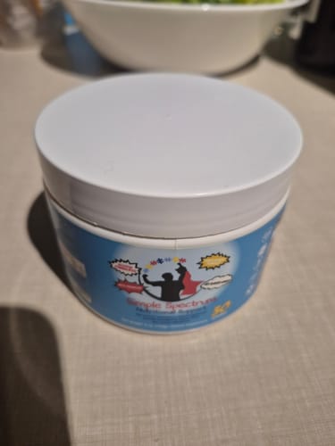 Customer's white and blue tub of Simple Spectrum Nutritional Support Supplement sitting on a table.