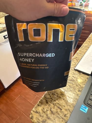 Customer holding the black pouch of SuperCharged Honey in a kitchen.