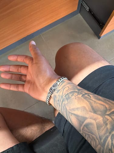 Cliente usando la Pulsera Cuban 8mm en su muñeca sobre un brazo tatuado.