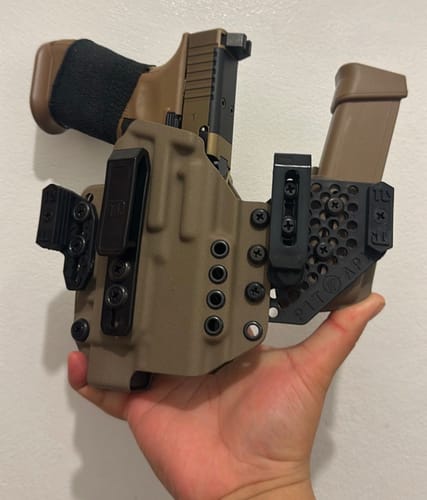 Customer holding the modular, tan APX holster with a gun and magazine secured, highlighting its many adjustment options.
