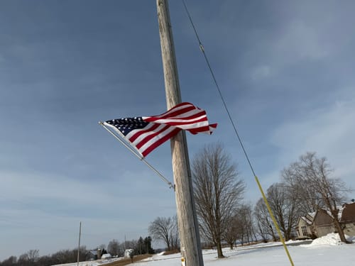 Reviewer's Ultra Heavy Duty American Flag waving on a utility pole in a snowy, windy location.