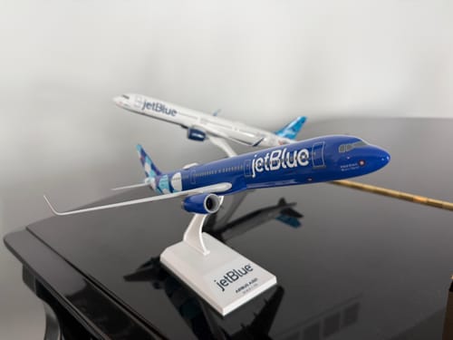 Customer's blue SKYMARKS JETBLUE A321 model on its display stand, with a second model plane blurred in the background.