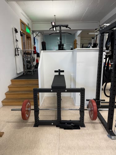 Customer's sturdy Riot Seal Row Bench set up in a gym, with a barbell and red weight plates underneath.