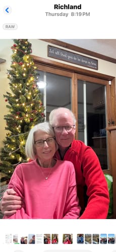 Customers smiling with their custom 'CREATE YOUR MELODY' sign hanging in their home above a doorway, next to a Christmas tree.