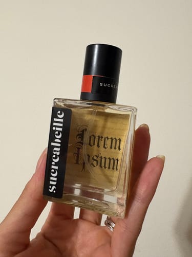 Customer's hand holding the square glass bottle of Lorem Ipsum perfume.