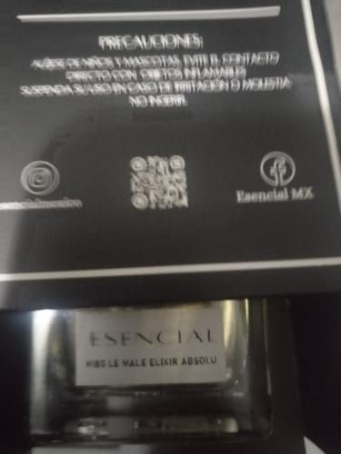 Primer plano de un cliente del perfume Esencial, mostrando el frasco de vidrio dentro de su caja negra.