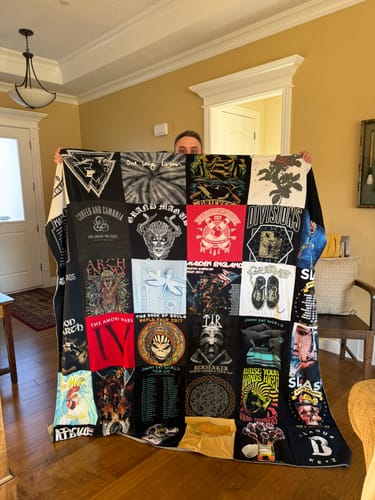 Customer holding up a large Premium T-Shirt Quilt made from various music concert t-shirts.