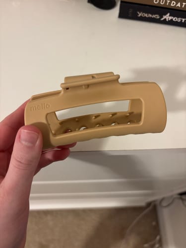 Reviewer's hand holding the rectangular cloud clip in a neutral latte color.