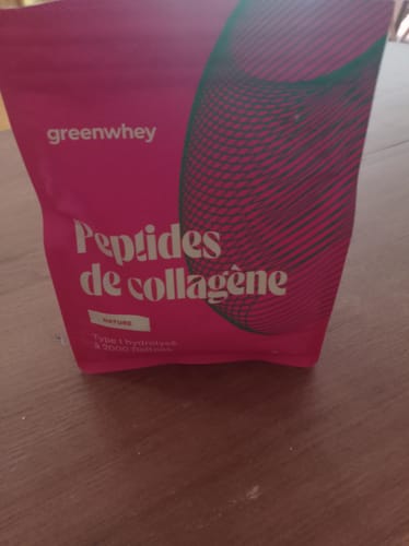 Un client montre le sachet rose de Peptides de Collagène posé sur une table en bois.