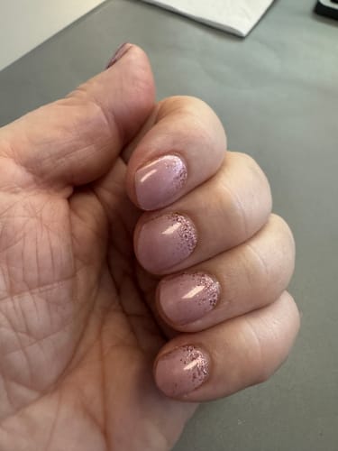 Kundin zeigt ihre kurzen Nägel mit den staubrosa „Cupcake Sprinkles“ UV-Gel-Nagelfolien mit Rosé-Glitzer.