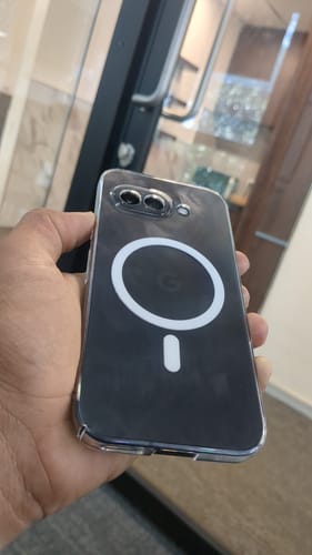 Reviewer holding a smartphone inside a clear case with a white magnetic charging ring.