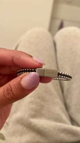 Close-up of a customer holding the Tethered Link Bracelet, focusing on the engraved slide-in magnet clasp.