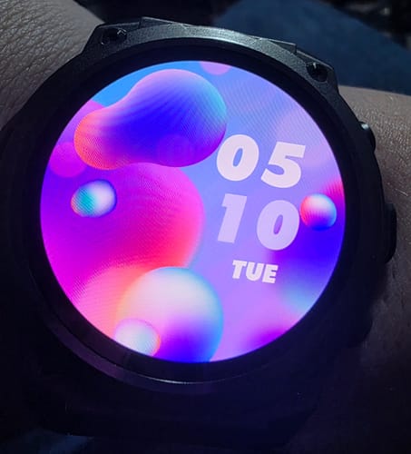Close-up of a customer's Gard Pro Ultra 3 watch on their wrist, showing a colorful abstract watch face with the time and date.