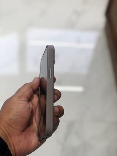 Customer holding the graphite grey Signature Leather Magsafe Case, showing the slim side profile.