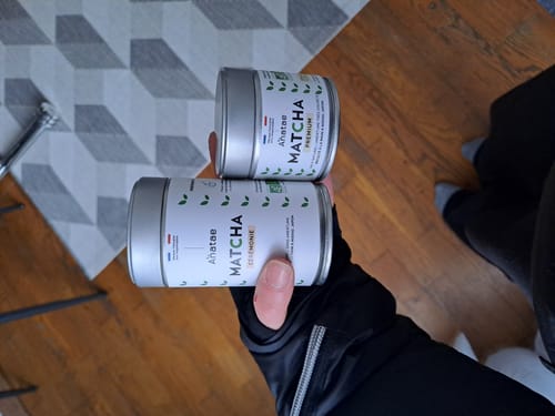 Client tenant ses deux boîtes de thé matcha Anatae, Cérémonie et Premium, dans sa main.