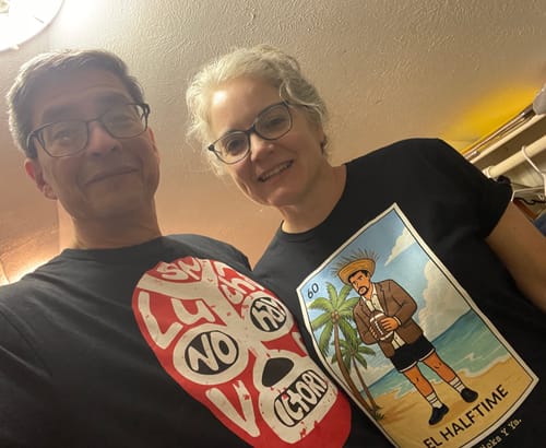 Customer smiling while wearing the black El Halftime OG T-Shirt with a colorful Lotería card graphic.
