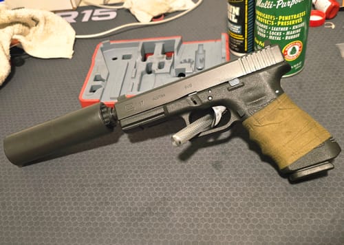 Customer's OD Green Raid Tape wrapped around the grip of a black handgun with a suppressor.