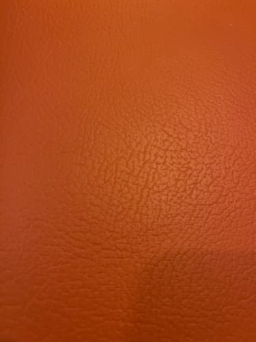 Rezensent zeigt eine Nahaufnahme einer orangefarbenen, strukturierten Oberfläche.