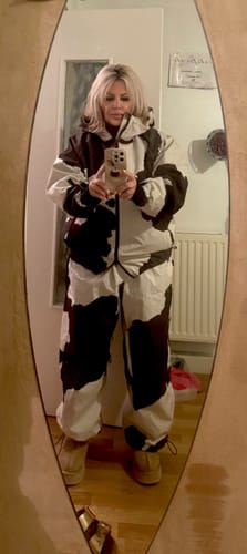 Reviewer taking a mirror selfie in a full snowsuit, showing the baggy snow pants with a black and white pattern.