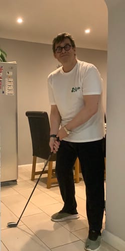 Reviewer posing with a golf club while wearing the white Disney Mickey Through the Ears crewneck tee.