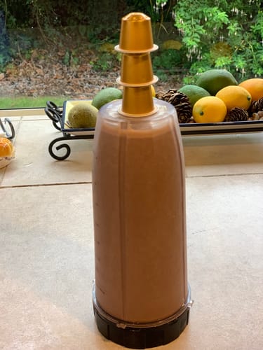 Reviewer's iced mocha in a blender cup, with the three gold Blend 14 capsules used to make it stacked on top.