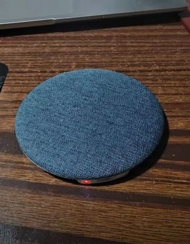 Customer's blue fabric Litlamp™ S1 Pillow Speaker on a wooden table, with a red indicator light showing.