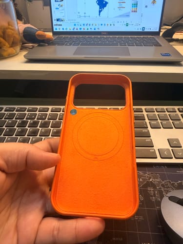Reviewer showing the inside of the Ember Orange Magsafe Case with its MagSafe ring and NFC chip visible.