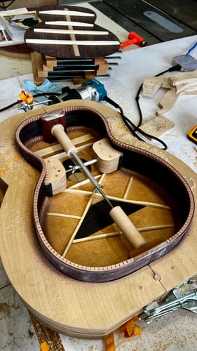 Reviewer in a workshop using a radiused sanding dish to assemble the body of a guitar.