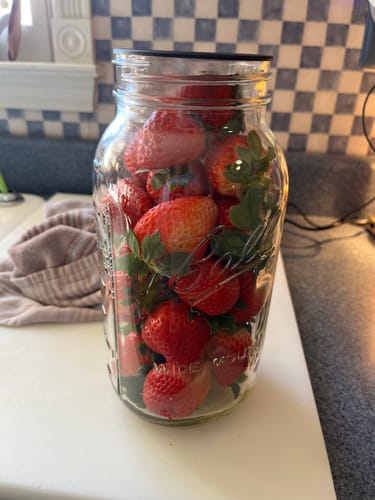 Reviewer's wide-mouth mason jar filled with fresh strawberries on a kitchen counter.